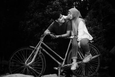 Couple sitting on old bicycle