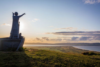 Statue on field against sky