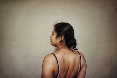 Rear view of woman looking away against wall