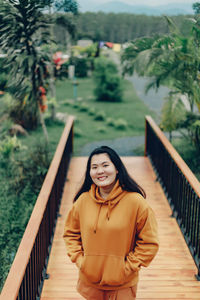 Portrait of young woman standing on footbridge