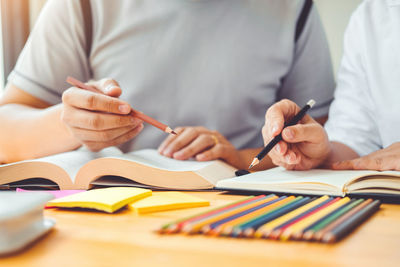 Midsection of man reading book on table