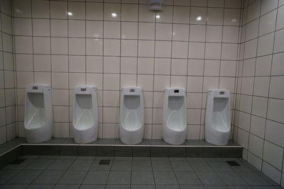 Urinals on tiled wall in public restroom
