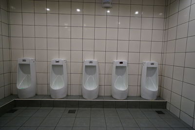 Urinals on tiled wall in public restroom