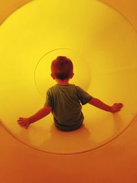 Full length rear view of boy standing on slide