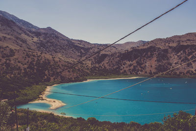 Scenic view of sea and mountains against clear blue sky