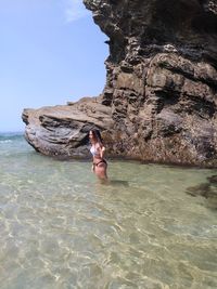 Teenage girl by rock at beach