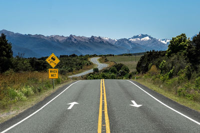 Road sign and zigzag road in new zealand against clear blue sky