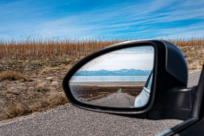 Reflection of cloudy sky on side-view mirror of car