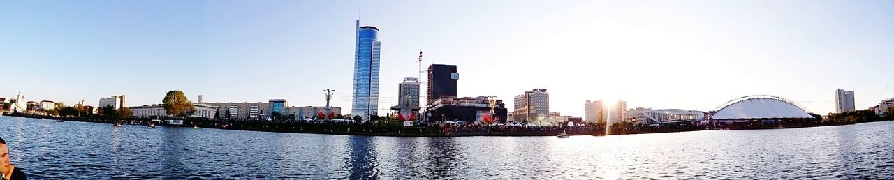 Panoramic view of city by river against clear sky