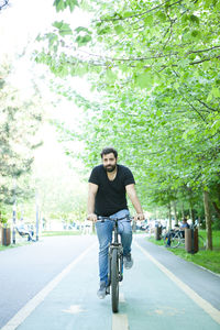 Portrait of young man riding bicycle on road
