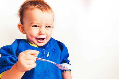 Portrait of happy boy with messy face against white background