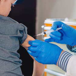 Cropped hands of doctor injecting syringe to boy in hospital