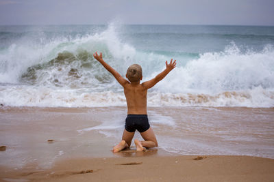 Full length of young woman jumping at beach