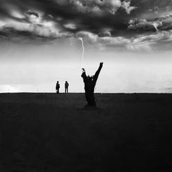 Silhouette people on field against sky