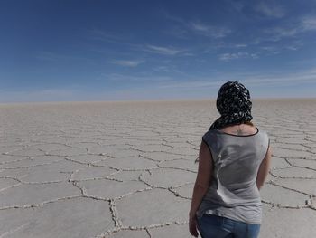 Rear view of woman standing on sand at desert