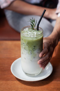 Cropped image of person holding drink on table