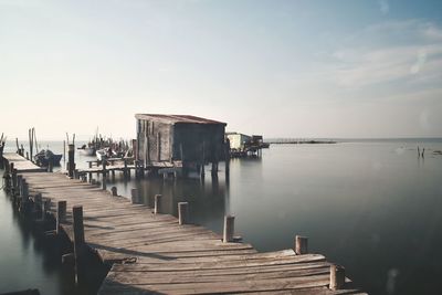 Wooden jetty on pier over sea against sky