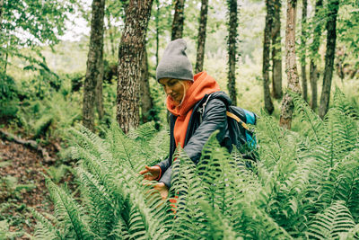 Young woman hiker making her way through the ferns in the forest