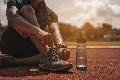 Low section of man tying shoes while sitting on running track