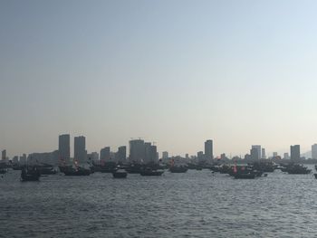 Sea and buildings in city against clear sky