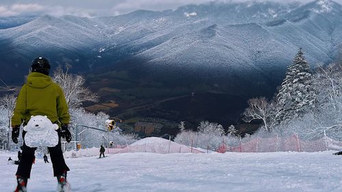 Rear view of man walking on snow covered mountain