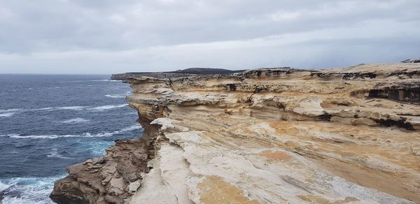 Rock formation by sea against sky
