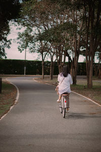 Rear view of man riding bicycle on road