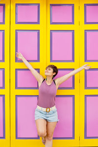 Portrait of young woman standing against wall