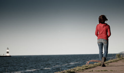 Rear view of man looking at sea against clear sky