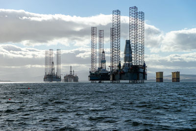 Cranes in sea against sky