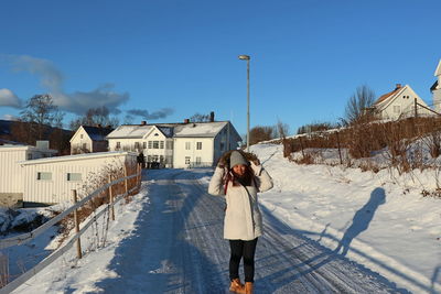 Rear view of woman standing on snow covered houses