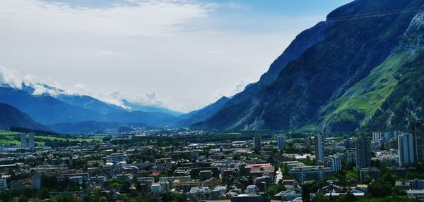 Aerial view of townscape and mountains against sky