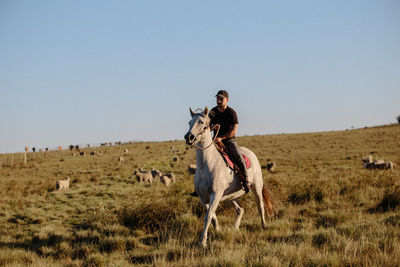 Man riding horse on field against clear sky