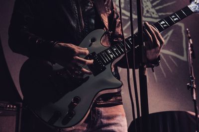 Midsection of man playing guitar