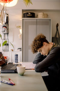 Tired boy reading book while studying at home