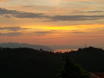 Scenic view of silhouette mountains against orange sky