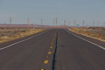 Electricity pylons by road against sky