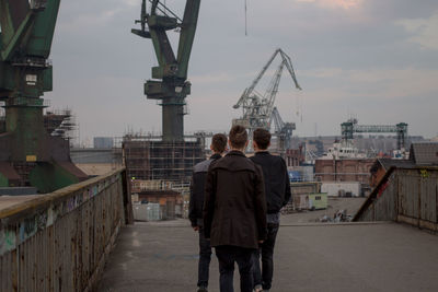 Rear view of men standing on bridge in city