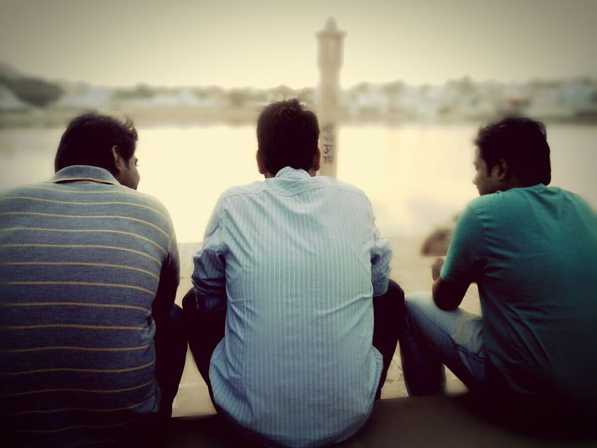 rear view, lifestyles, men, togetherness, casual clothing, leisure activity, bonding, focus on foreground, sitting, love, standing, boys, waist up, three quarter length, person, friendship, looking at view