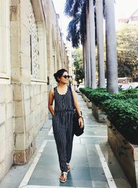 Full length of smiling young woman standing on footpath