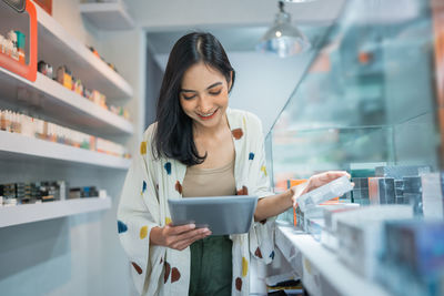 Young woman using mobile phone while standing in office