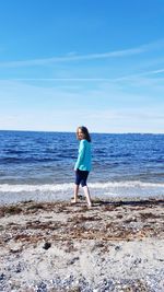 Portrait of smiling girl standing at beach against sky