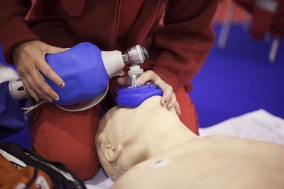 Midsection of man practicing on cpr dummy at hospital