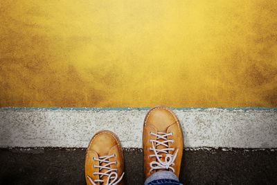 Low section of person standing on yellow concrete