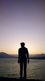 Silhouette of woman in sea at sunset