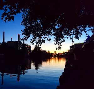 Reflection of silhouette trees on water in city