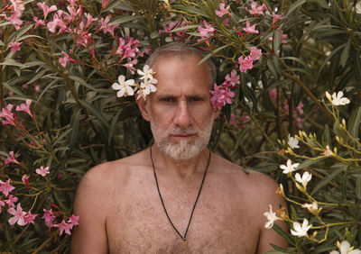 Portrait of shirtless man standing on flowering plants