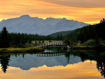 Scenic view of lake and mountains against sky during sunset