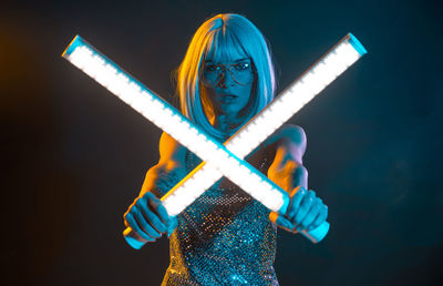 Woman in dress dancing with illuminated lights against black background