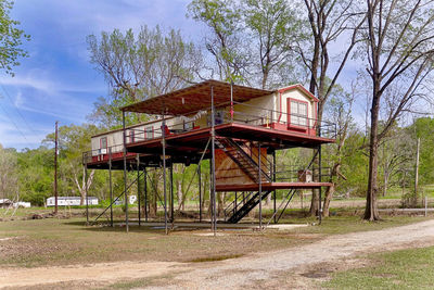 Abandoned house amidst trees on field against sky